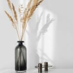 a black vase with some dry grass in it